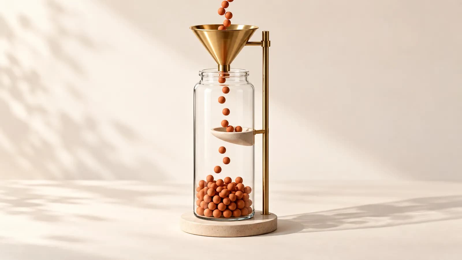 A brass funnel pouring terracotta beads into a glass jar, a few beads caught on a ledge