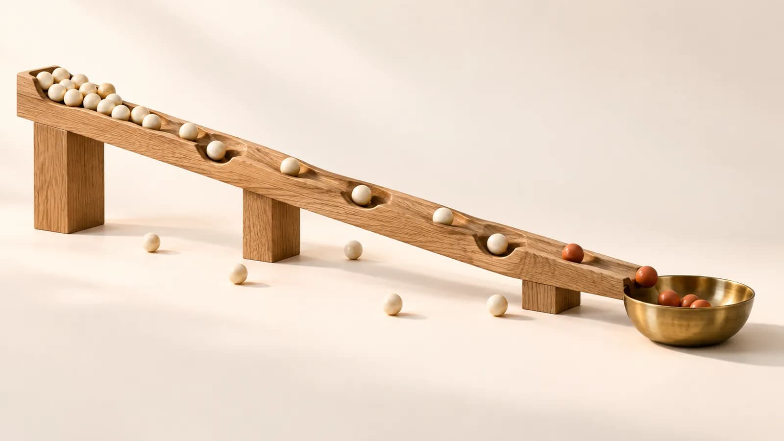 Marbles rolling down an oak track, many stopping on the way and a few reaching a brass cup