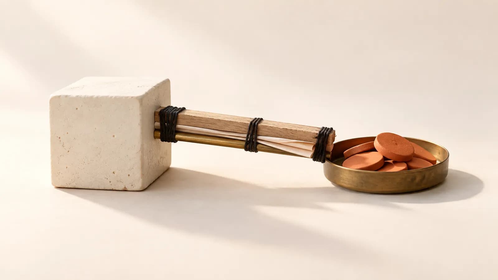 A makeshift bridge of oak, paper and brass linking a ceramic block to a tray of terracotta discs