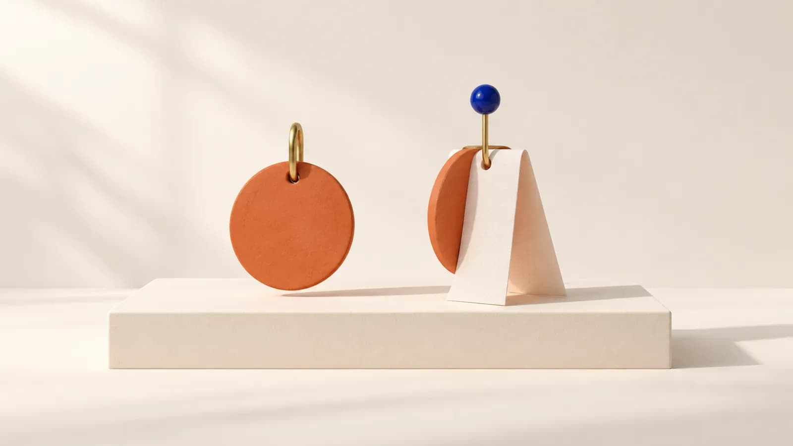 A lone terracotta disc on a brass loop beside a paper card and disc pinned together