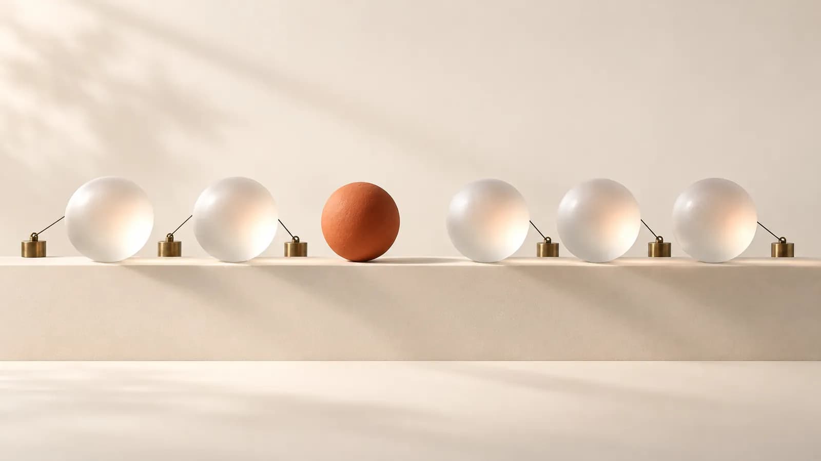 Frosted glass spheres tied by fine threads to brass weights, one terracotta sphere left untied