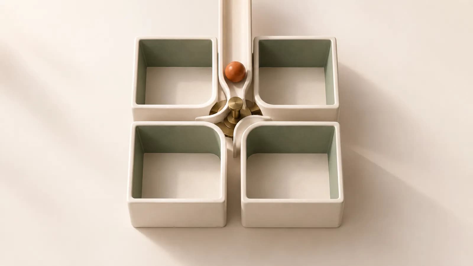 A terracotta marble rolling past a brass switch into one of four ceramic compartments